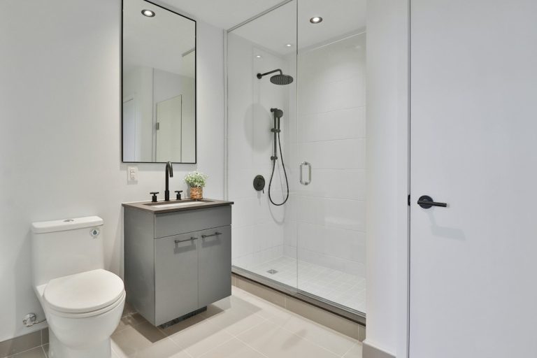 Walk-in shower with glass enclosure and tiled walls